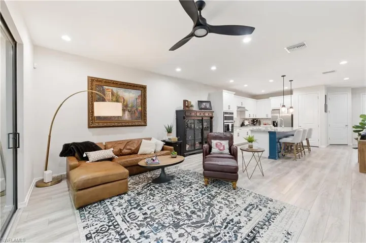 Living area with a ceiling fan, light wood-style flooring, and recessed lighting