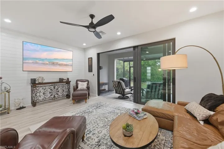 Living room with ceiling fan, wood finished floors, recessed lighting, and wooden walls