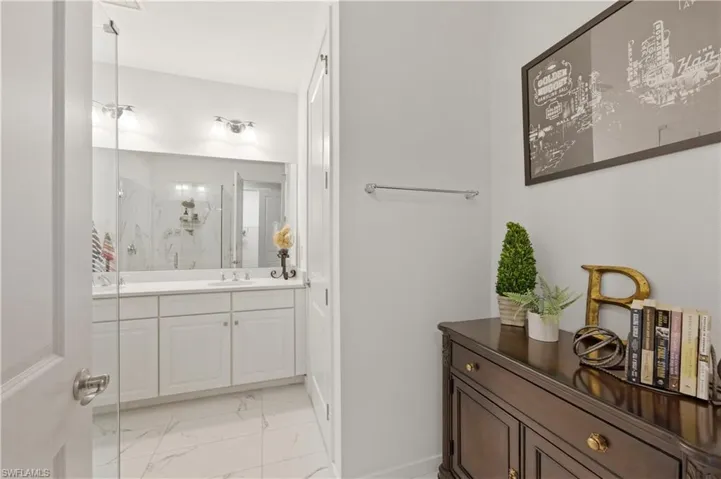 Full bathroom with a marble finish shower, vanity, and light marble finish flooring