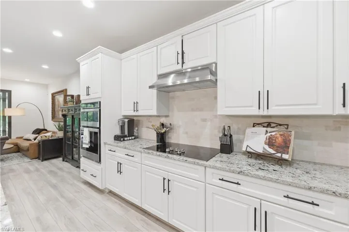 Kitchen with white cabinets, light stone counters, recessed lighting, and light wood-type flooring
