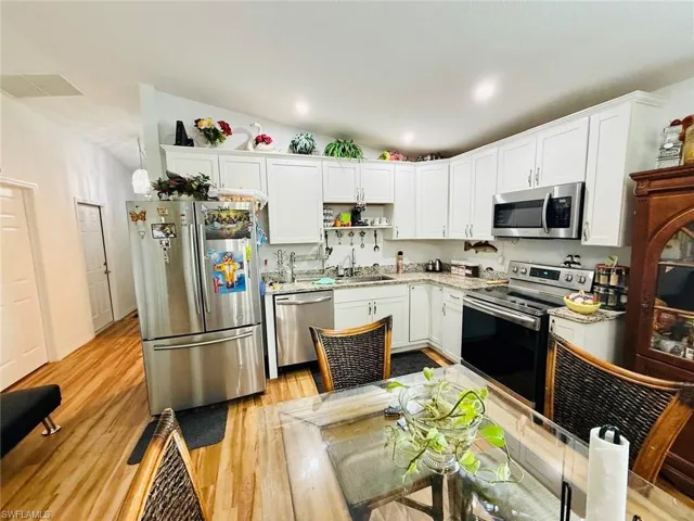 Kitchen featuring appliances with stainless steel finishes, white cabinets, open shelves, light wood finished floors, and recessed lighting