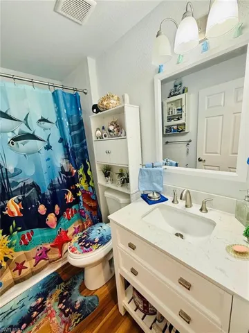 Full bath with a textured wall, vanity, wood finished floors, a shower with shower curtain, and a textured ceiling