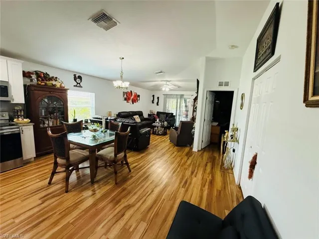 Dining space featuring healthy amount of natural light, light wood-type flooring, a ceiling fan, and a chandelier