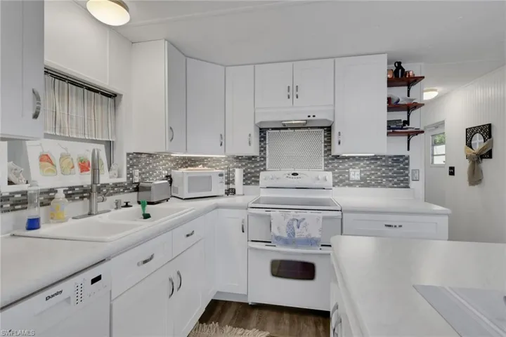 Kitchen featuring white appliances, white cabinets, light countertops, and open shelves
