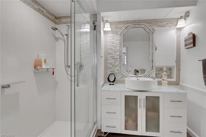 Full bath with vanity, a shower stall, wainscoting, and tasteful backsplash