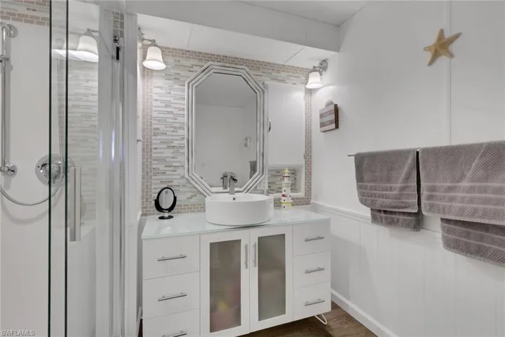 Full bathroom featuring vanity, wainscoting, a stall shower, and dark wood-type flooring