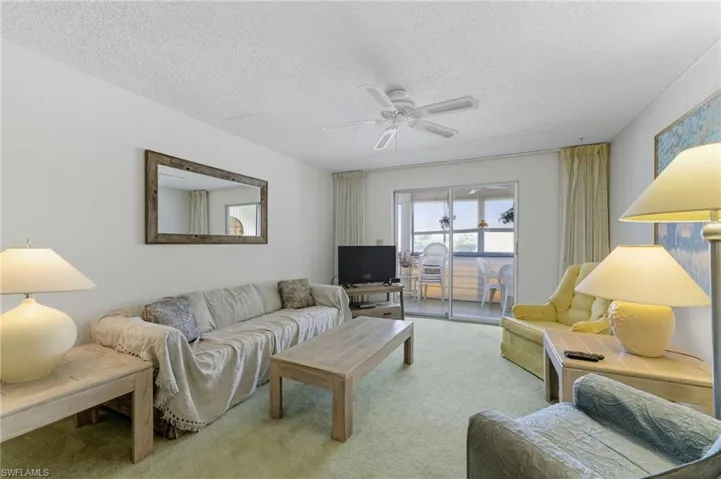 Living area featuring carpet, ceiling fan, and a textured ceiling.