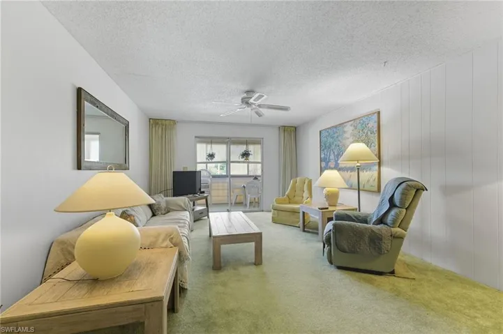 Living area with carpet, a textured ceiling, and a ceiling fan.