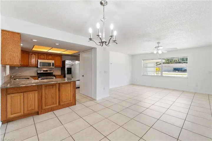 Kitchen with light stone countertops, light tile patterned floors, appliances with stainless steel finishes, a peninsula, and a sink