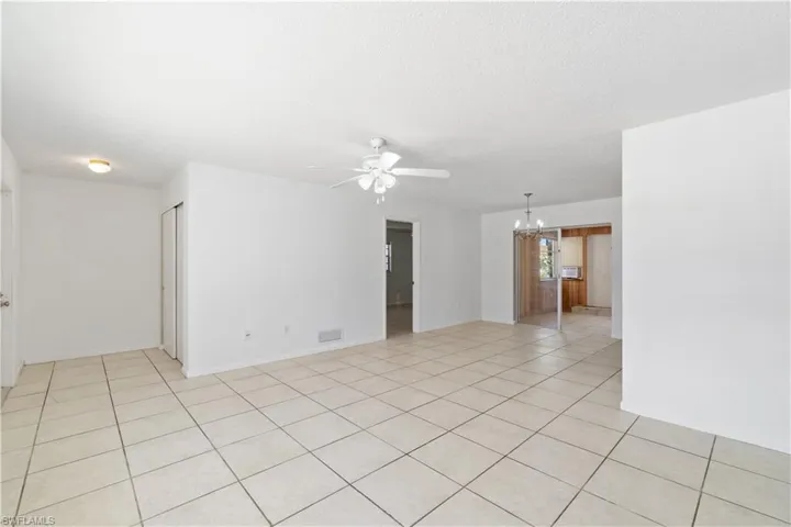 living room with light tile patterned floors, ceiling fan with notable chandelier