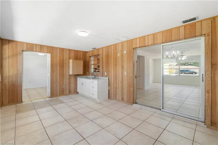 Secondary Living Space/Den for multi-generational family or rental income featuring a kitchen, a sink, wooden walls, light tile patterned flooring, and light countertops