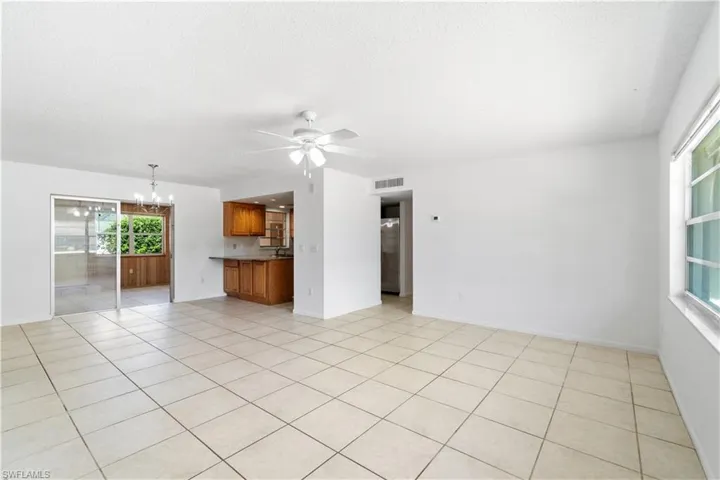 Unfurnished living room featuring light tile patterned floors, ceiling fan with notable chandelier