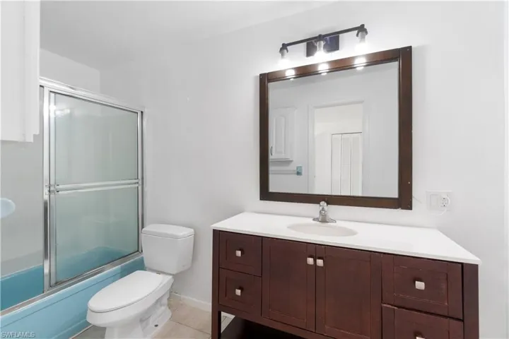Secondary Primary Suite Bathroom with enclosed tub / shower combo, tile patterned floors, toilet, and vanity