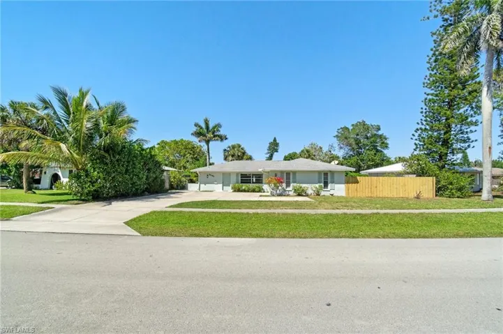 View of front of home featuring concrete driveway, fence, and a front yard