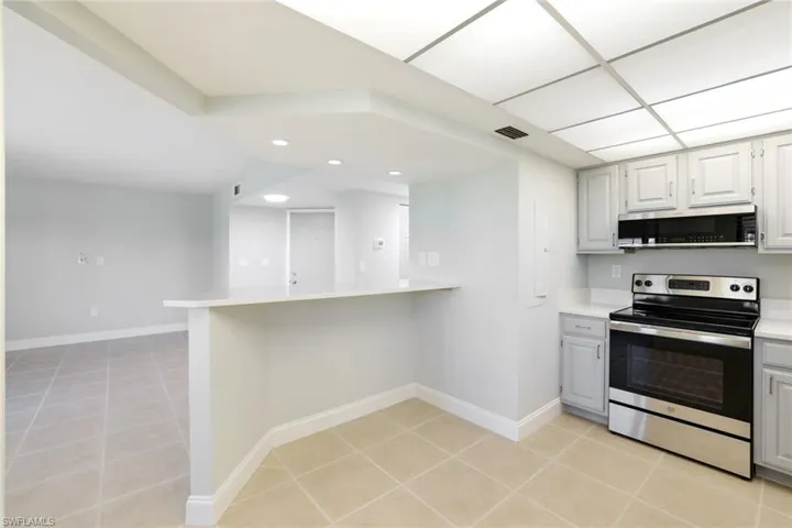 Kitchen with appliances with stainless steel finishes, light tile patterned floors, a peninsula, and a kitchen breakfast bar