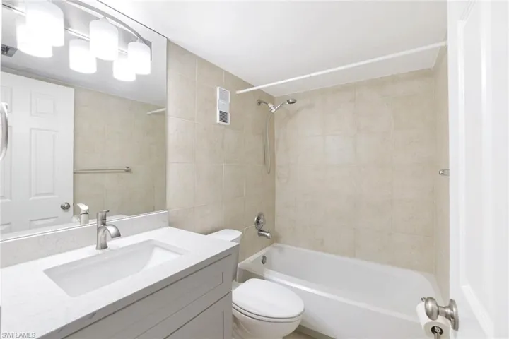 Bathroom featuring tub / shower combination, tile walls, and vanity