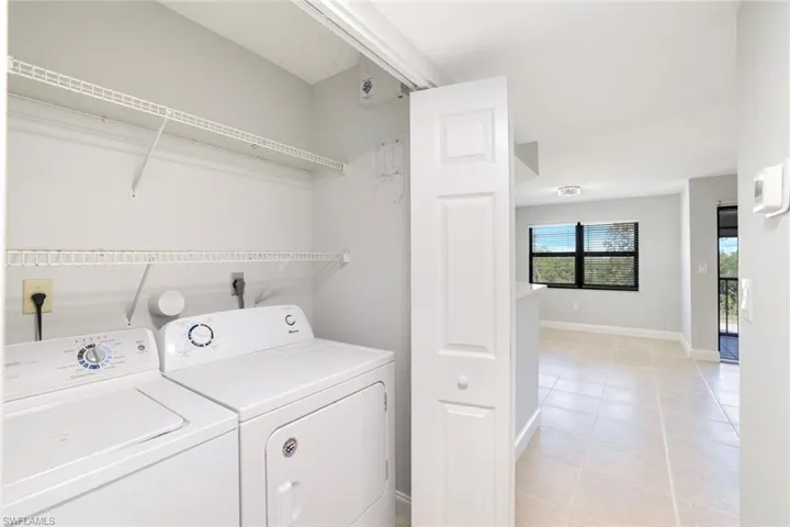 Laundry area with light tile patterned floors and washing machine and dryer