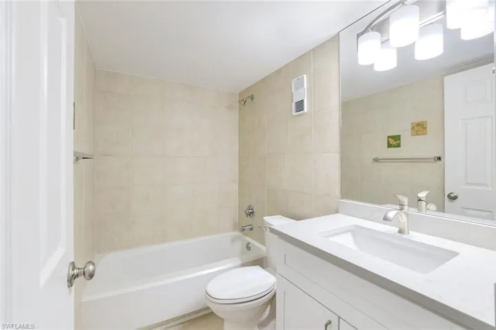 Bathroom featuring shower / washtub combination, vanity, and tile walls