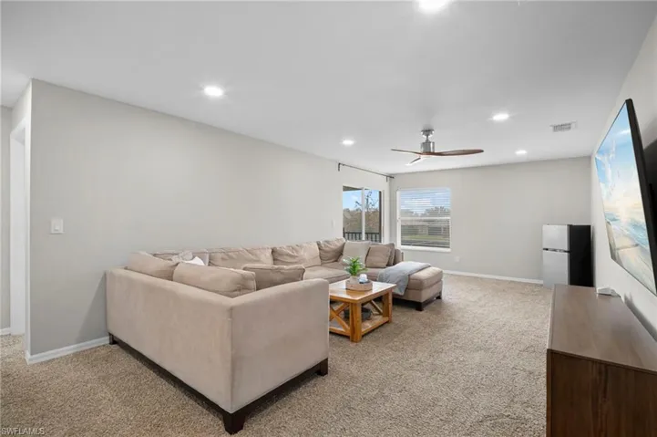 Living area with light colored carpet, recessed lighting, and ceiling fan