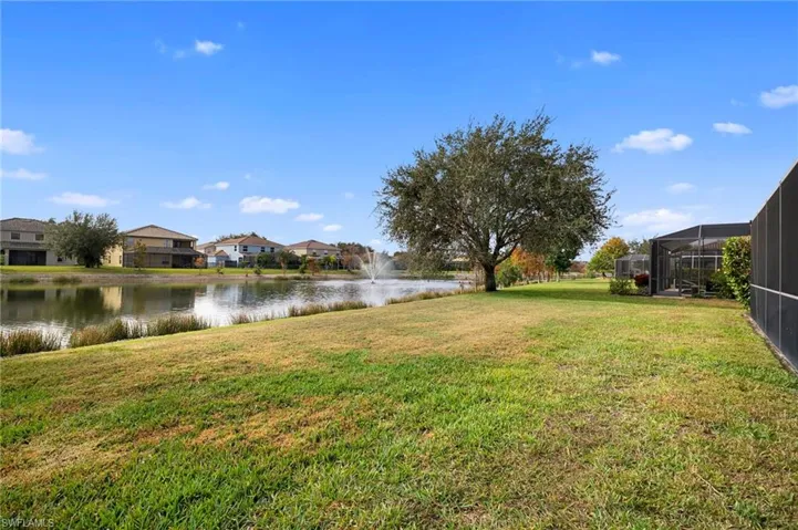 View of grassy yard with a water view, a sunroom, a residential view, and glass enclosure
