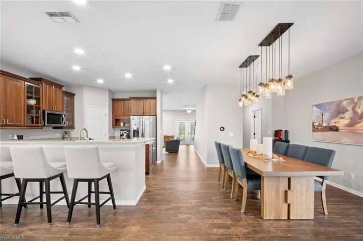 Kitchen with a breakfast bar, glass insert cabinets, brown cabinets, recessed lighting, and decorative light fixtures