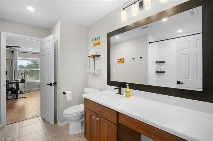 Bathroom with vanity, light tile patterned flooring, recessed lighting, and a shower