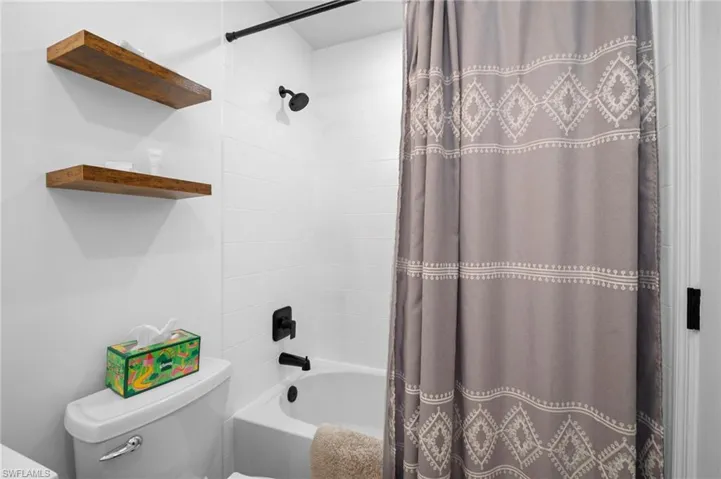 Full bathroom with shower / bath combination with curtain and toilet