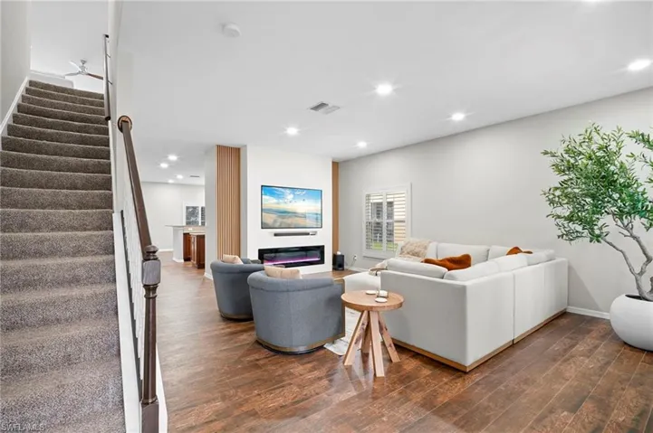 Living room with stairs, recessed lighting, dark wood finished floors, and a glass covered fireplace