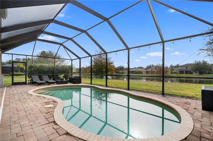 Outdoor pool with a lawn, a lanai, a sunroom, and a water view