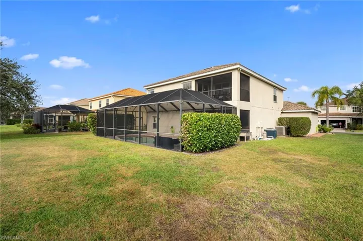Rear view of property featuring a sunroom, glass enclosure, a lawn, and stucco siding