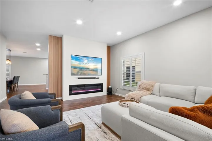 Living area with recessed lighting, a glass covered fireplace, and wood finished floors
