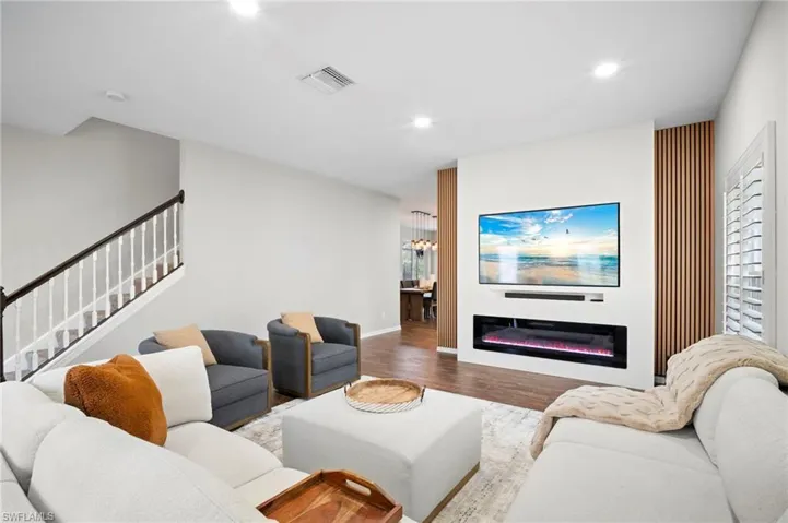 Living area with recessed lighting, a glass covered fireplace, wood finished floors, a chandelier, and stairs
