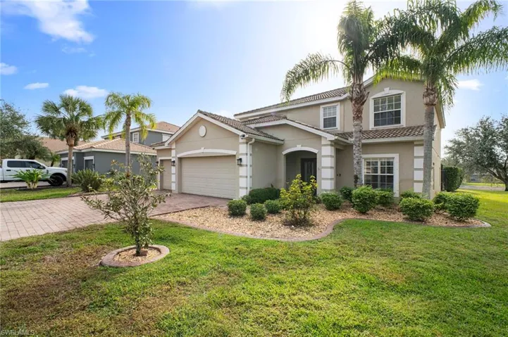 View of front of house with stucco siding, a front yard, and decorative driveway