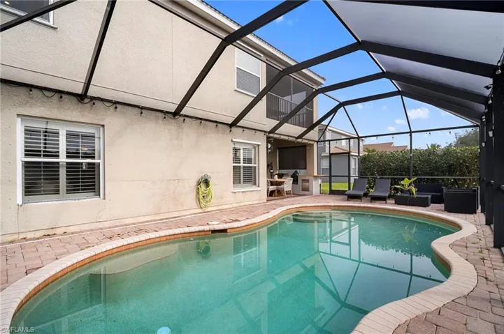 Swimming pool featuring a sunroom, a patio area, and glass enclosure