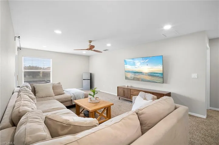 Living area with light carpet, a ceiling fan, and recessed lighting