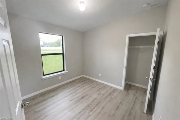 Unfurnished bedroom featuring light wood-type flooring and a spacious closet