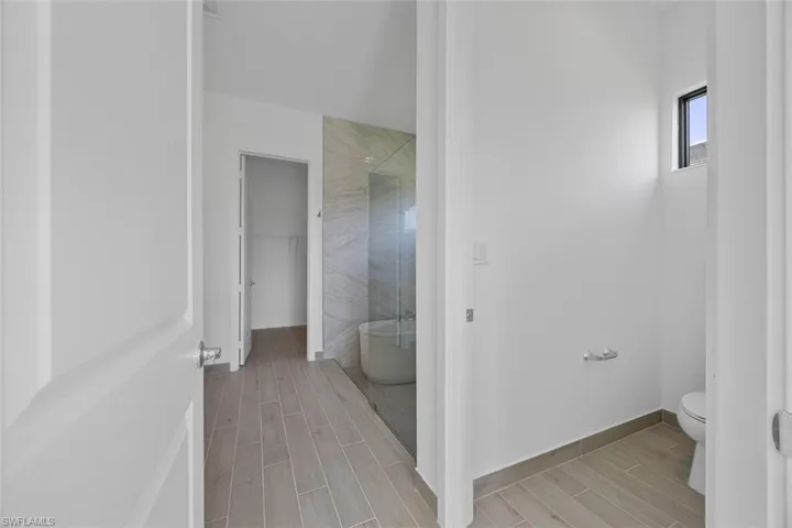 Full bathroom with wood tiled floor, a soaking tub, toilet, and tiled shower