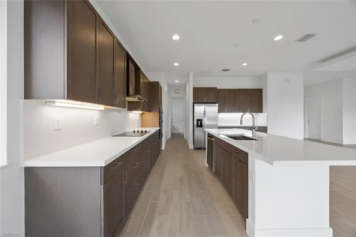 Kitchen featuring dark brown cabinets, a sink, light wood-style flooring, stainless steel appliances, and recessed lighting