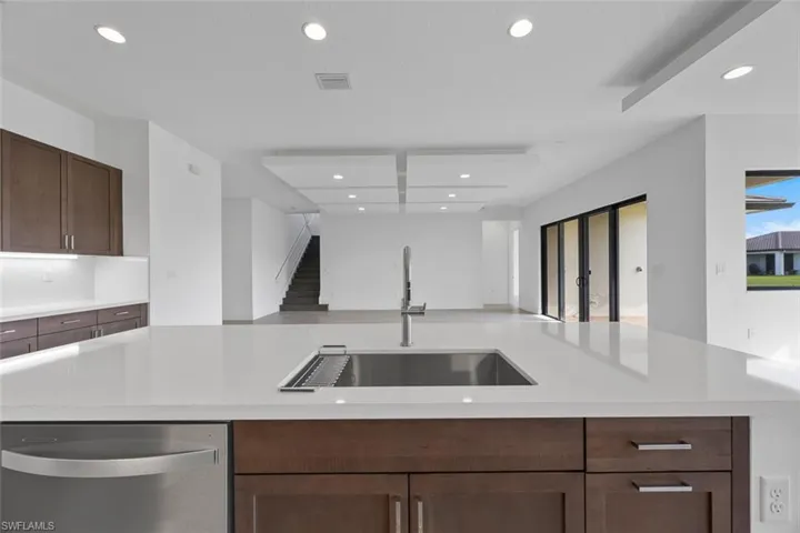 Kitchen with stainless steel dishwasher, open floor plan, recessed lighting, light countertops, and a sink