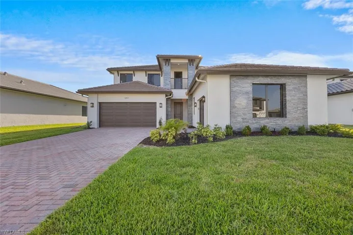 Prairie-style home with a garage, stucco siding, a front lawn, and decorative driveway