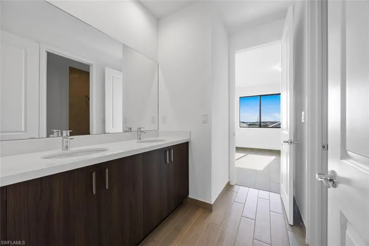 Full bath featuring double vanity, baseboards, a sink, and wood tiled floor