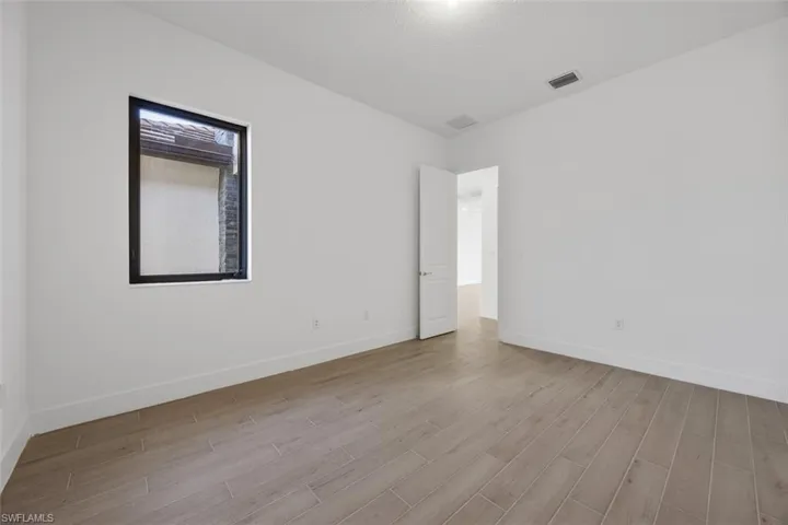 Empty room featuring baseboards, visible vents, and wood finished floors