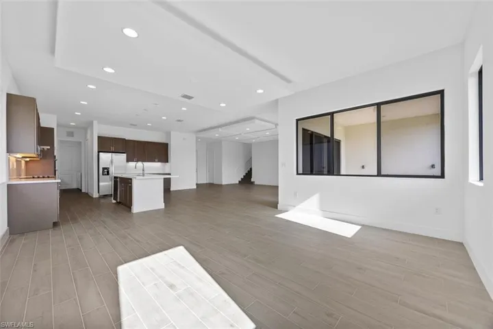 Unfurnished living room featuring a sink, recessed lighting, light wood finished floors, and stairs