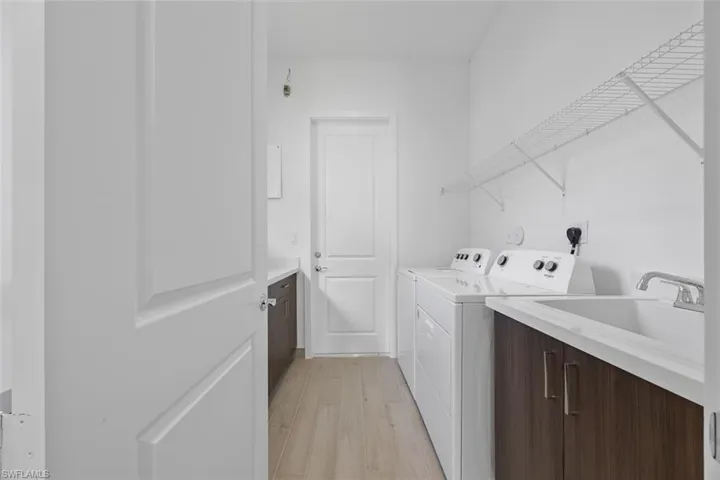 Washroom with separate washer and dryer, a sink, and light wood finished floors