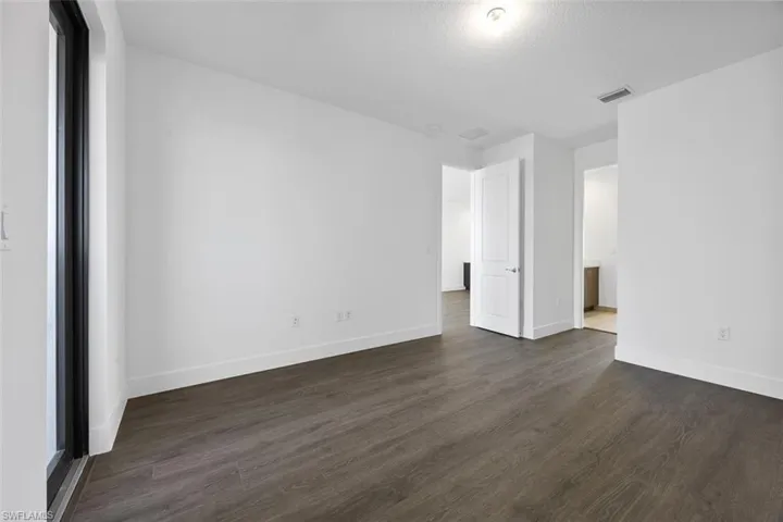Unfurnished bedroom with visible vents, dark wood finished floors, and baseboards