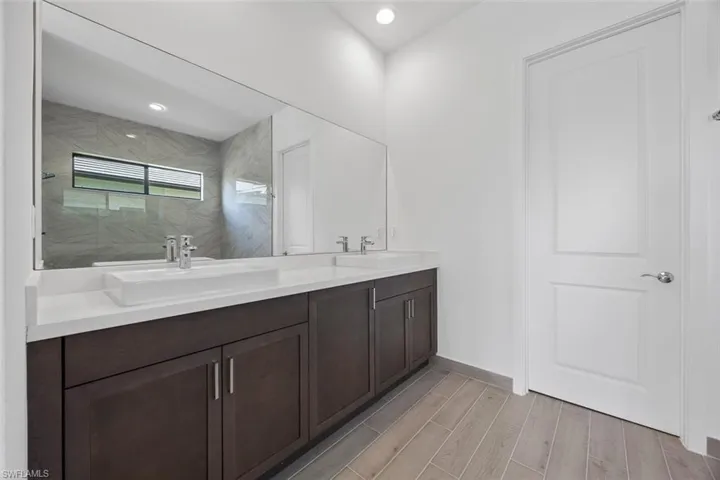 Full bathroom featuring double vanity, a sink, wood finish floors, and tiled shower