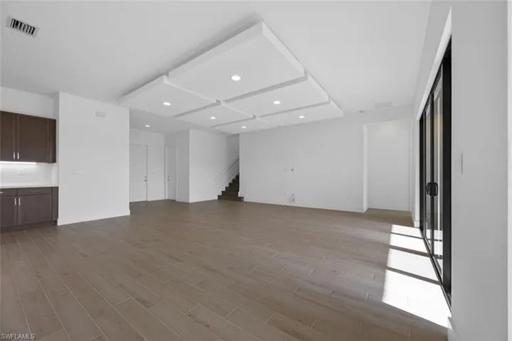 Unfurnished living room featuring recessed lighting, visible vents, light wood-style flooring, and stairway