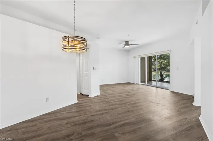 Empty room with ceiling fan with notable chandelier and dark hardwood / wood-style flooring