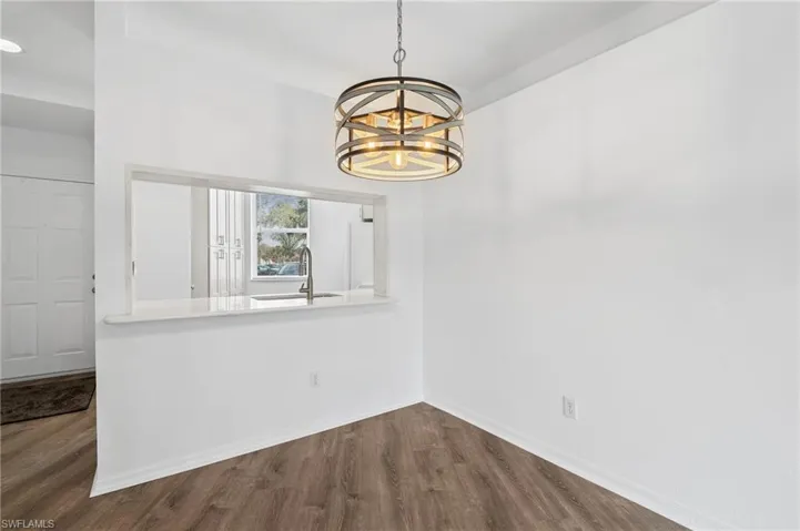 Unfurnished dining area with wood-type flooring, a notable chandelier, and sink