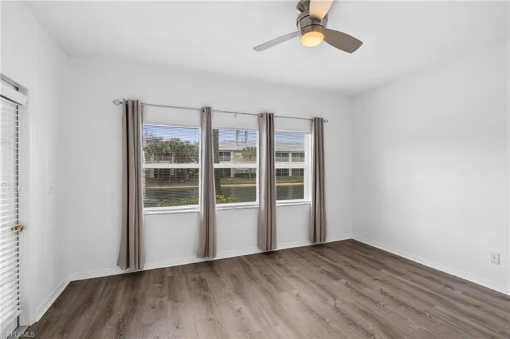 Empty room with ceiling fan and dark hardwood / wood-style flooring